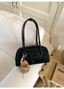 Detail of black vintage shoulder bag with white contrast stitching and puppy charm