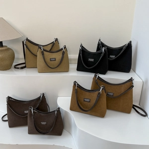 Close-up of four colors of suede tote bags with brand label and adjustable straps