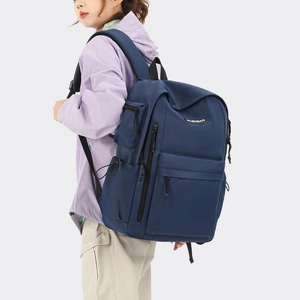 Detail view of navy blue travel backpack showing side profile and multiple zipper pockets