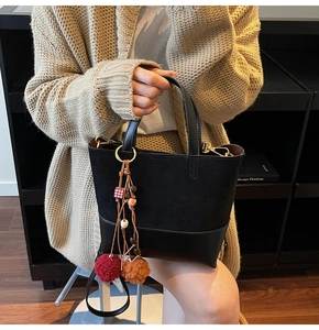 Detail of vintage black patchwork bucket bag with colorful plush charms and gold hardware