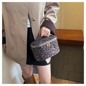 Détail d'une trousse à maquillage léopard avec fermeture éclair dorée et poignée