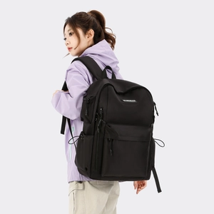 Side view of model wearing a large black nylon backpack with drawstrings and side pockets