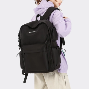 Side view of large black nylon travel backpack with wide padded straps on a model