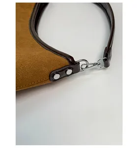 Detail of silver metal shoulder strap buckle and brown leather texture on hobo bag