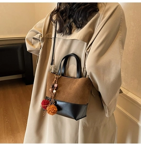 Detail of vintage tote bag with suede texture, leather trim and colorful tassel charm