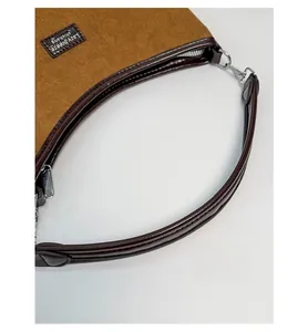 Detail view of brown suede underarm bag with leather handles and silver metal hardware