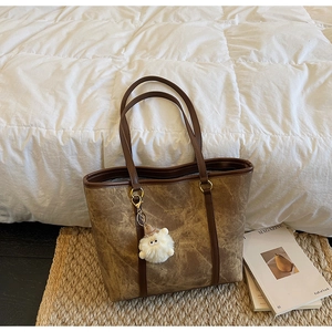 Detail of retro brown tote bag featuring marble texture and white plush charm accessory