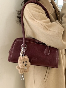 Vintage burgundy bowling shoulder bag with white contrast stitching and plush dog charm