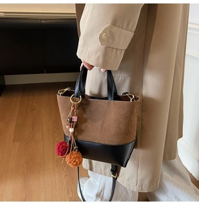 Detail of vintage patchwork handbag with brown suede texture and plush ball charm