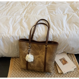 Detail of vintage brown textured tote bag with a white plush sheep charm on woven mat