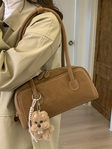 Brown suede bowling bag with puppy charm accessory worn with autumn trench coat