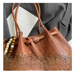 Detail of woven brown tote bag featuring luxury V-pattern texture and beaded strap charms