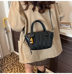Detail der schwarzen geflochtenen Bucket Bag mit bunten Perlenquasten und Rundgriffen