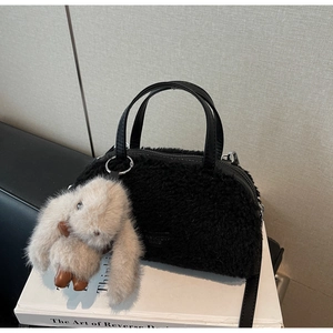 Details der schwarzen Plüschhandtasche mit PU-Griffen und süßem Hasenanhänger