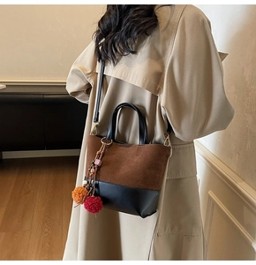 Detail of retro bucket bag featuring brown suede texture and colorful pom-pom charm decoration