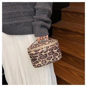 Détail de la trousse de maquillage léopard avec double fermeture éclair dorée en main