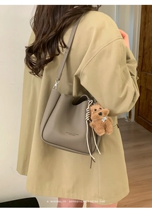 Detailed close-up of dark taupe lychee leather bucket bag with a cute brown bear charm