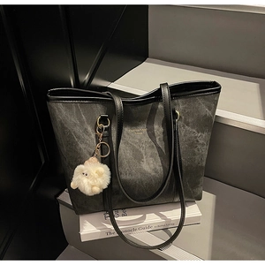 Detail of marble texture black tote bag with gold lettering and white lamb charm
