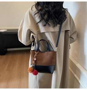 Detail of vintage bicolor tote bag featuring brown suede and black leather with pompom