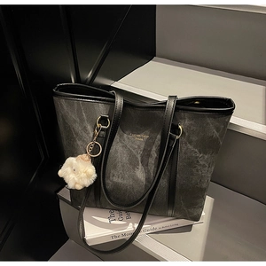 Detail of stone-washed denim tote bag with leather strap and plush sheep charm decoration