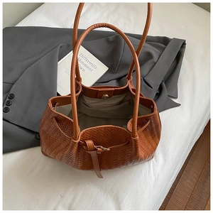 Gros plan du sac cabas marron tissé montrant la texture en V et le fermoir magnétique