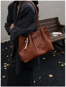 Détail du sac cabas tressé caramel avec breloque perlée et texture en V