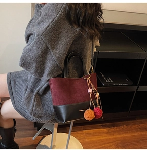 Detail of vintage bucket bag with wine red suede, black leather and tassel charms