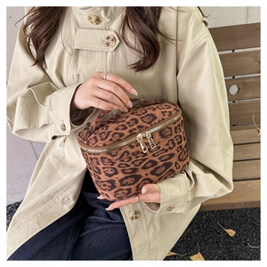 Détail d'une trousse de maquillage léopard avec double fermeture éclair dorée et poignée
