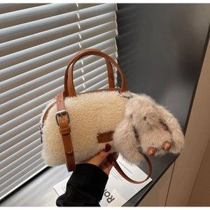 Detail der flauschigen cremeweißen Zylindertasche mit braunem Kunstlederband und Hase