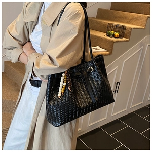 Détail d'un sac cabas noir tressé avec perles en bois et bandoulière réglable