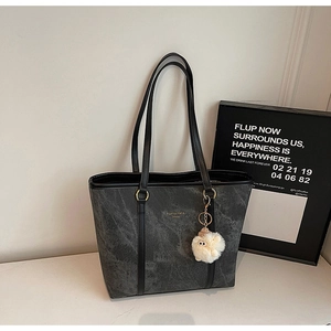 Detail of grey marble pattern tote bag with gold logo and plush pompom charm