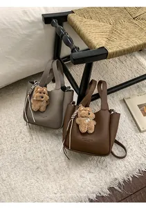 Detail of lychee pattern leather bucket bags with plush puppy charms and logo