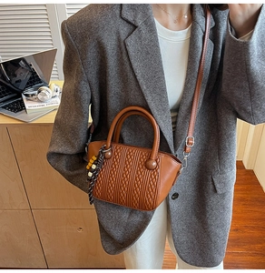 Close-up of retro brown bucket bag with embossed weave texture and tassel detail