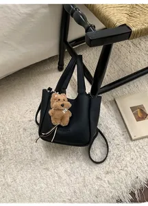 Close-up of black lychee grain leather bucket bag with cute brown teddy bear charm