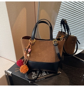 Detailed close-up of brown bucket bag featuring colorful pompom and bead charms