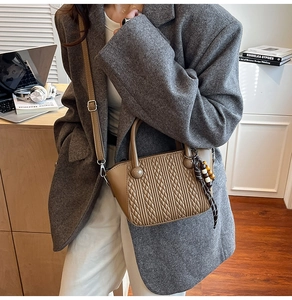 Chic brown quilted bucket bag styled with a gray blazer in a modern office setting