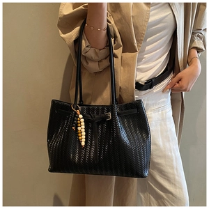 Détail du sac cabas noir à texture tressée avec breloque perlée et fines bandoulières
