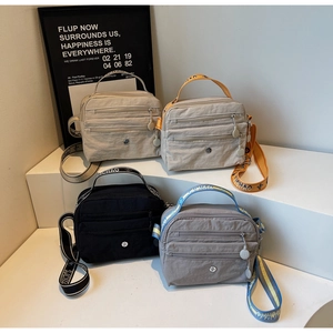 Detail of multi-pocket nylon crossbody bags in four colors with adjustable logo straps