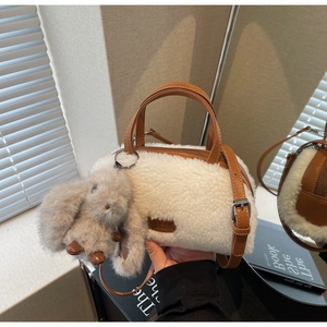 Detailansicht der weißen Plüsch-Zylindertasche mit braunen Ledergriffen und Hasenanhänger