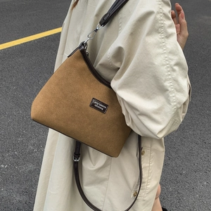 Close-up of a vintage brown crossbody bag with matte texture on a beige trench coat