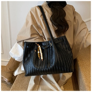 Détail du tissage noir sur ce grand sac cabas avec un pendentif décoratif en perles de bois
