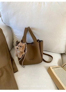 Detailed view of brown lychee leather bucket bag with a cute plush dog pendant