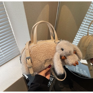 Detailaufnahme der cremefarbenen Plüschtasche mit Hasenanhänger und Leder-Logo-Etikett