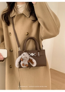 Close-up of vintage brown crossbody bag with silver heart buckle and plush bunny charm