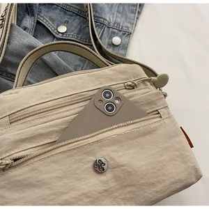 Front zipper pocket of a khaki nylon crossbody bag showing large phone capacity