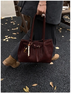 Détail d'un sac cabas tressé marron foncé avec charm en perles et sangle en cuir rétro