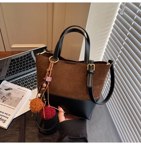 Detail of color-block tote bag in brown suede and black leather with decorative tassel
