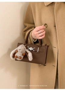 Detail of retro dark brown leather handbag featuring a silver heart clasp and rabbit charm