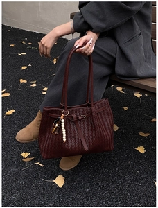 Détail d'un sac cabas tissé bordeaux avec des perles dans un décor de forêt d'automne