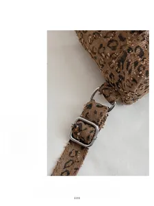 Close-up of adjustable silver metal buckle and leopard print strap on canvas backpack